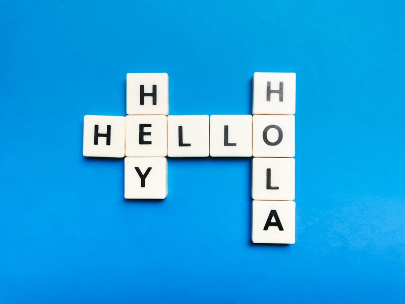 Letter tiles spelling Hello, Hola and Hey on a blue background