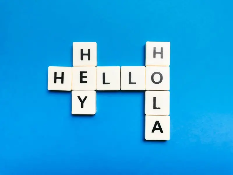 Letter tiles spelling Hello, Hola and Hey on a blue background